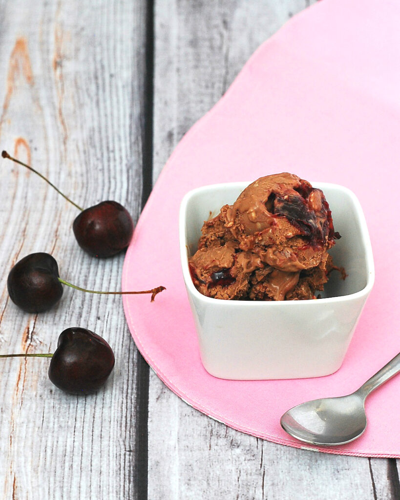 Rich chocolate cheesecake ice cream with swirls of roasted cherries with a hint of vanilla — it's easy to make but so hard to stop eating! theredheadbaker.com