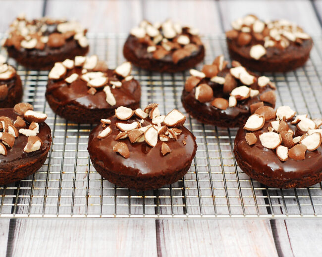 Chocolate malt baked donuts glazed in chocolate-malt glaze and topped with crushed malt candies are perfect for breakfast or dessert! TheRedheadBaker.com #TwelveLoaves
