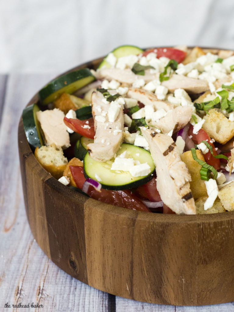 Greek Panzanella Salad is a perfect summer weeknight meal that combines tomato, red onion, cucumber, chicken and toasted bread with a homemade vinaigrette. TheRedheadBaker.com