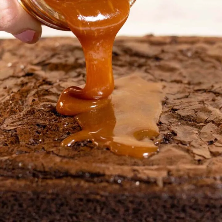 Salted caramel being poured on a baked sheet of brownies.