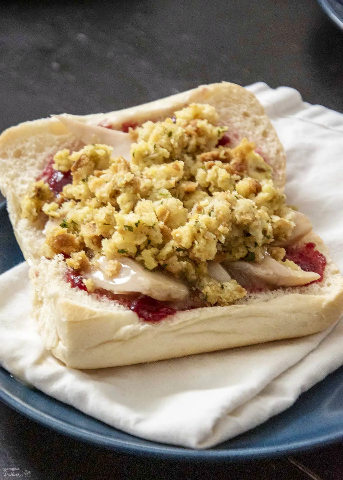 A Thanksgiving leftovers sandwich on a whtie napkin.