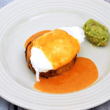 Celebrate #BrunchWeek with a fancy Eggs Benedict: a poached egg sits atop a crab cake, topped with tomato Hollandaise sauce, and served with avocado mash. theredheadbaker.com