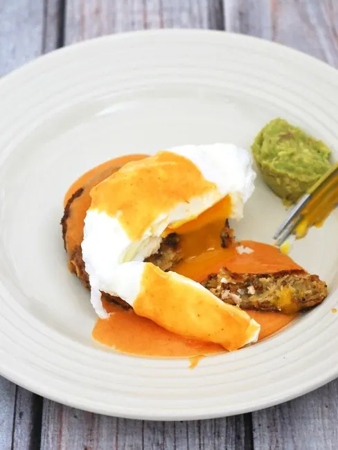 Celebrate #BrunchWeek with a fancy Eggs Benedict: a poached egg sits atop a crab cake, topped with tomato Hollandaise sauce, and served with avocado mash. theredheadbaker.com