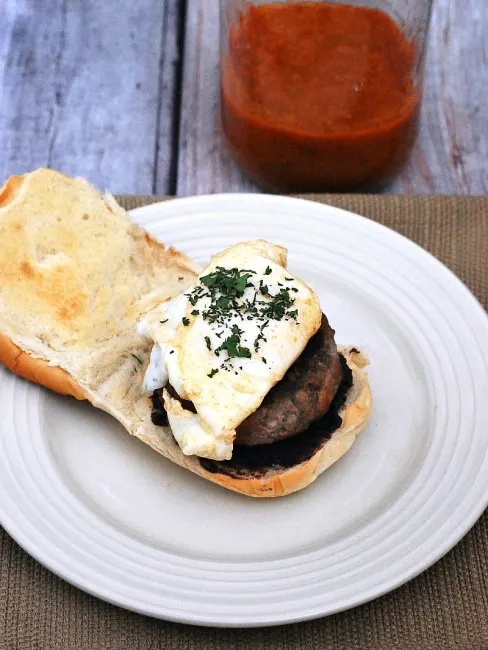 Add a kick to your brunch with huevos rancheros burgers! Spicy chorizo and beef burgers are topped with a poached egg and spicy huevos rancheros sauce. #BrunchWeek theredheadbaker.com