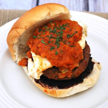 Add a kick to your brunch with huevos rancheros burgers! Spicy chorizo and beef burgers are topped with a poached egg and spicy huevos rancheros sauce. #BrunchWeek theredheadbaker.com