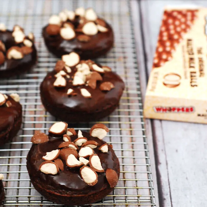 Chocolate malt baked donuts glazed in chocolate-malt glaze and topped with crushed malt candies are perfect for breakfast or dessert! TheRedheadBaker.com #TwelveLoaves