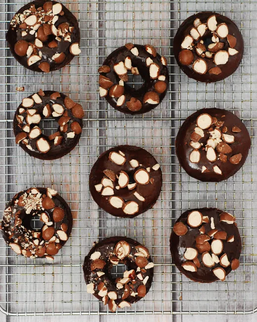 Chocolate malt baked donuts glazed in chocolate-malt glaze and topped with crushed malt candies are perfect for breakfast or dessert! TheRedheadBaker.com #TwelveLoaves