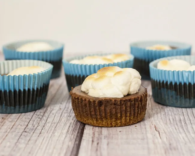 S'mores turn elegant in the form of mini chocolate cheesecakes with graham cracker crusts, topped with marshmallows toasted under the broiler. TheRedheadBaker.com #WhatsBaking