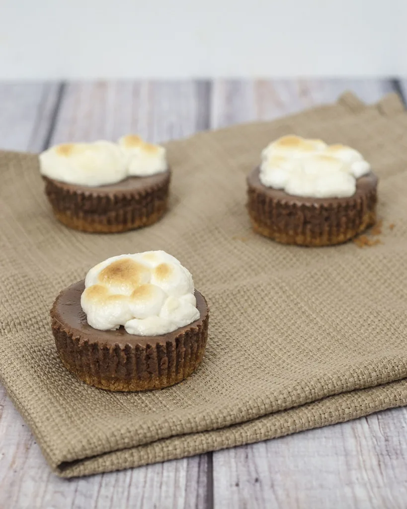 S'mores turn elegant in the form of mini chocolate cheesecakes with graham cracker crusts, topped with marshmallows toasted under the broiler. TheRedheadBaker.com #WhatsBaking