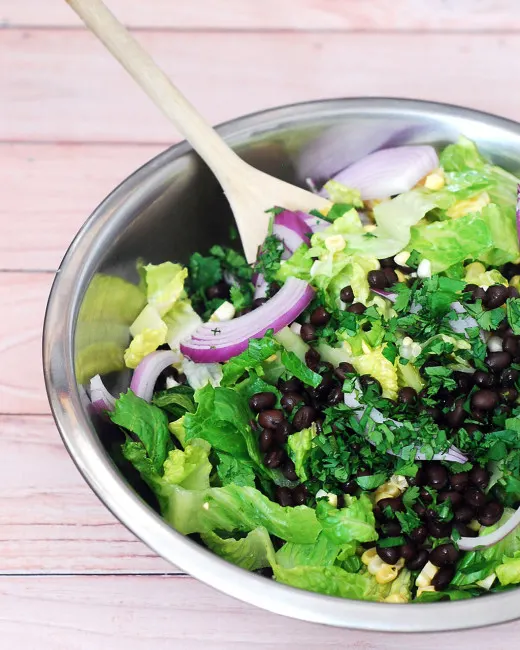 When the temperature rises, you need a meal that is filling, flavorful, and doesn't heat up your kitchen. This salad combines healthy veggies, beans, and a spicy dressing — no cooking required! #WeekdaySupper TheRedheadBaker.com