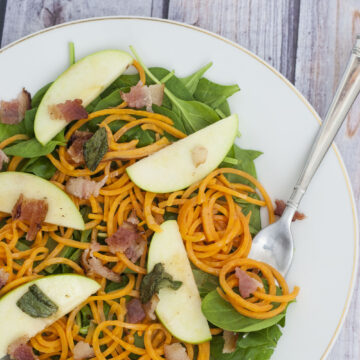 Sweet potato noodle salad swaps spiralized sweet potatos for pasta, served over spinach and apples with a delicious and tangy warm sage-brown-butter dressing. TheRedheadBaker.com