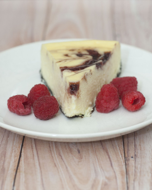 This incredibly rich and creamy white chocolate raspberry cheesecake has swirls of raspberry preserves — it looks difficult, but is to easy to make. #SundaySupper TheRedheadBaker.com