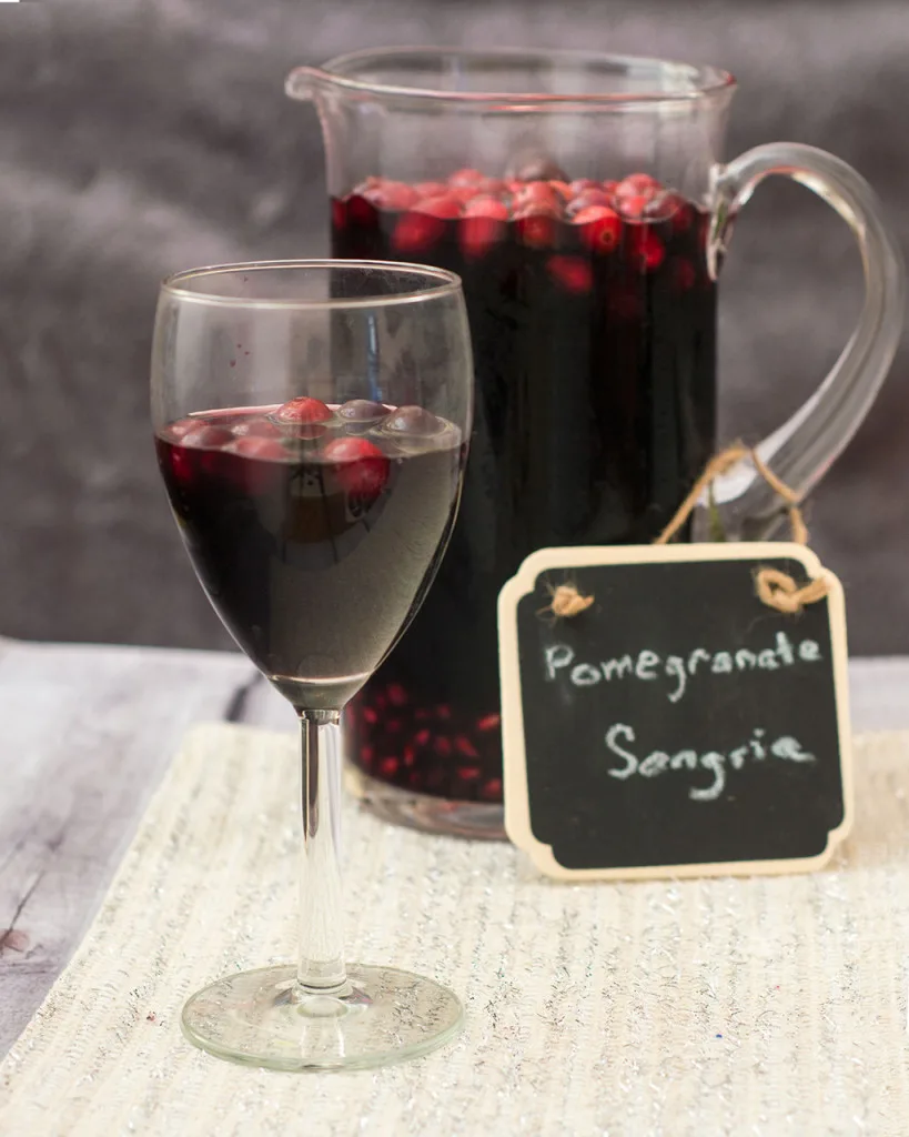 Pomegranate sangria combines fruity red wine with pomegranate and cranberry, with cinnamon for a hint of spice. Make a large batch a day ahead for a winning party cocktail! #SundaySupper TheRedheadBaker.com