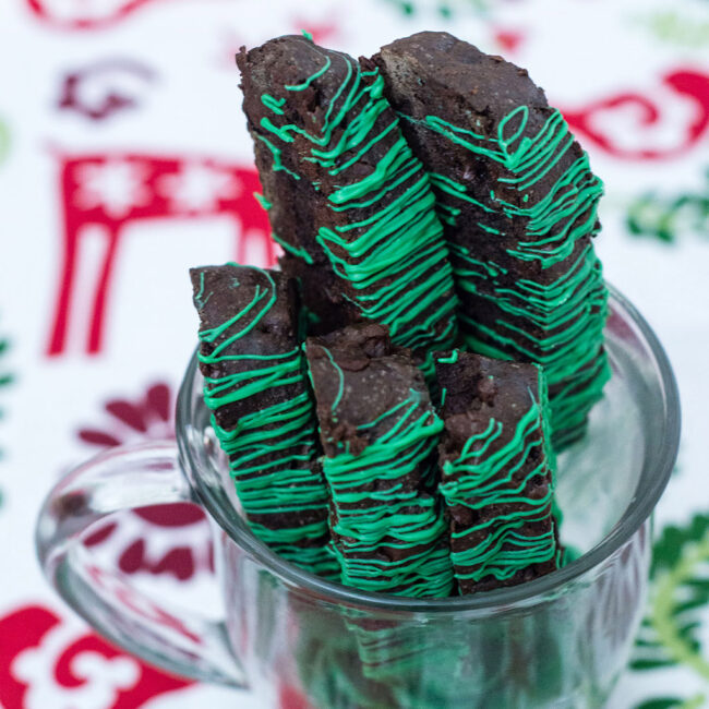 Italian-style biscotti is the perfect accompaniment for your afternoon cup of coffee! This cookie is flavored with dark chocolate cocoa powder and mint-flavored chocolate morsels. TheRedheadBaker.com #WhatsBaking