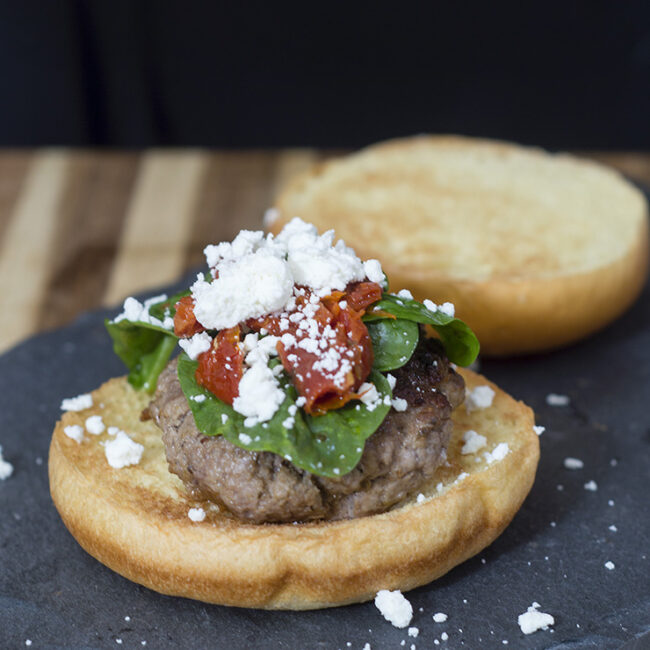 Lamb burgers are flavored with herbs and spices of Greece, then topped with spinach and sun-dried tomatoes tossed with lemon, and a sprinkle of feta. TheRedheadBaker.com