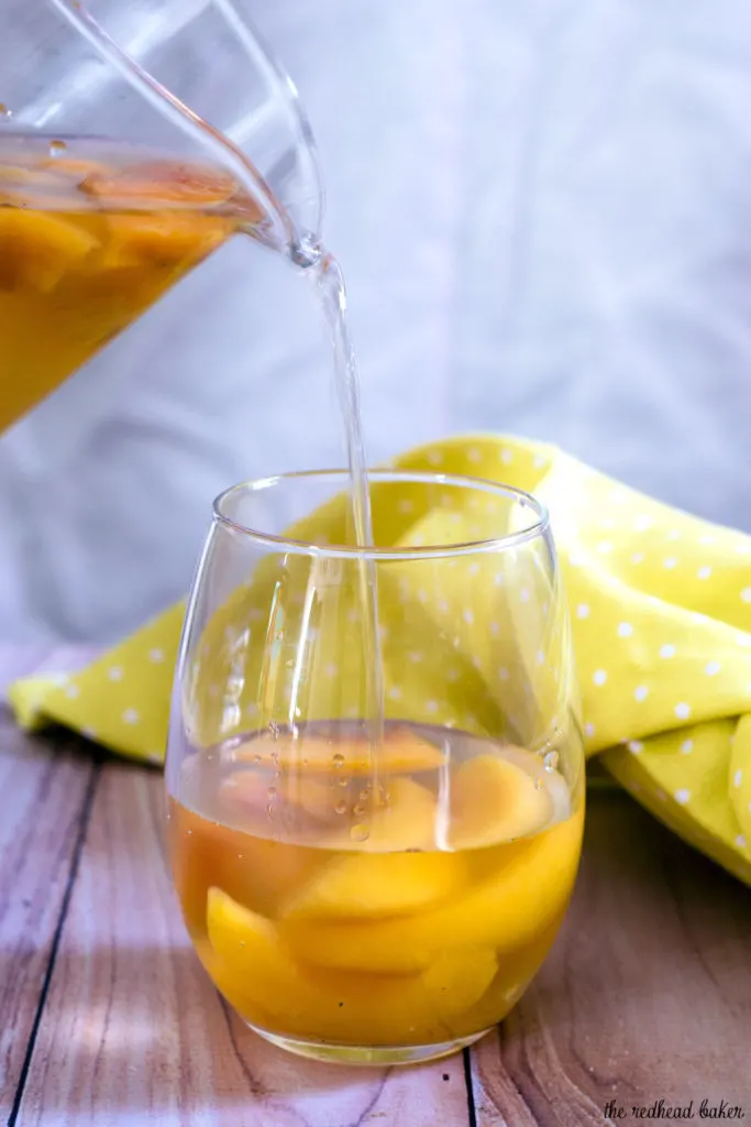 If you try one new cocktail this summer, make it this peach vanilla sangria. Crisp white wine is flavored with peaches, brandy and syrup infused with vanilla bean. #TheRedheadBaker