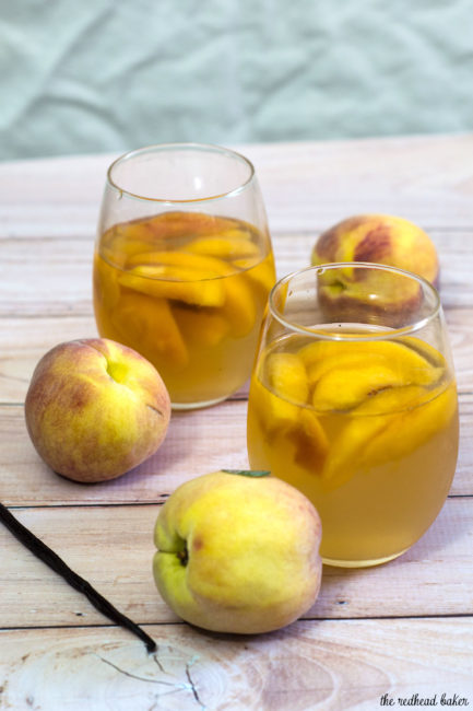 If you try one new cocktail this summer, make it this peach vanilla sangria. Crisp white wine is flavored with peaches, brandy and syrup infused with vanilla bean. #TheRedheadBaker