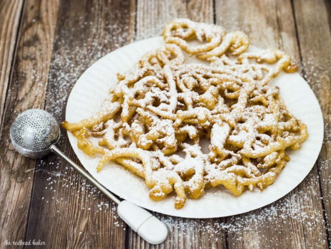 Boardwalk funnel cake takes me back to childhood vacations at a New Jersey beach. This warm deep-fried treat is dusted with powdered sugar and great for sharing! #SundaySupper TheRedheadBaker.com