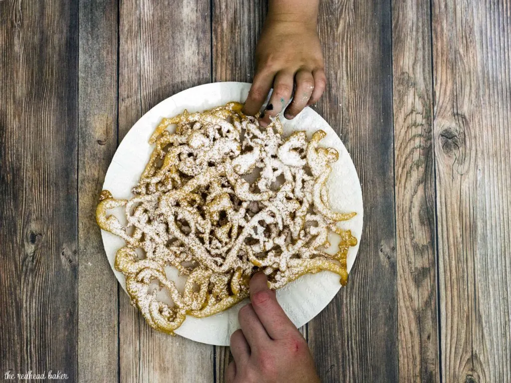 Boardwalk funnel cake takes me back to childhood vacations at a New Jersey beach. This warm deep-fried treat is dusted with powdered sugar and great for sharing! #SundaySupper TheRedheadBaker.com