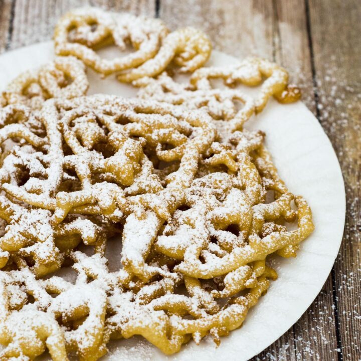 Boardwalk funnel cake takes me back to childhood vacations at a New Jersey beach. This warm deep-fried treat is dusted with powdered sugar and great for sharing! #SundaySupper TheRedheadBaker.com