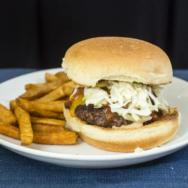 Carolina-style BBQ burgers are juicy beef patties topped with sharp cheddar cheese, tangy mustard- and vinegar-based BBQ sauce and coleslaw. #SundaySupper TheRedheadBaker.com