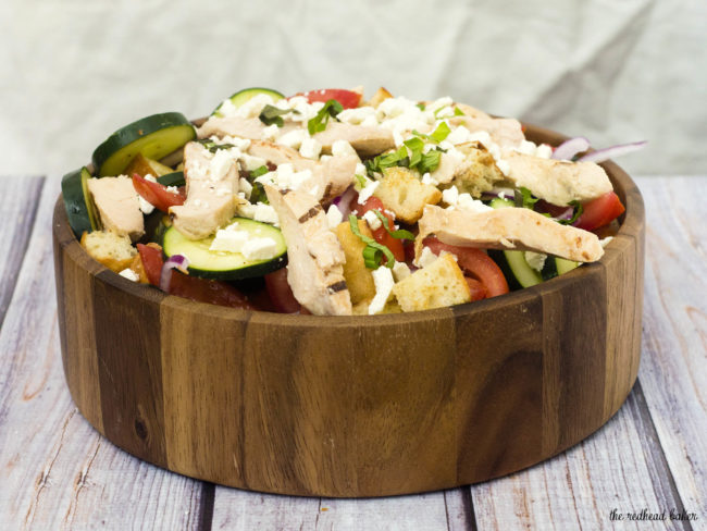 Greek Panzanella Salad is a perfect summer weeknight meal that combines tomato, red onion, cucumber, chicken and toasted bread with a homemade vinaigrette. The Redhead Baker.com