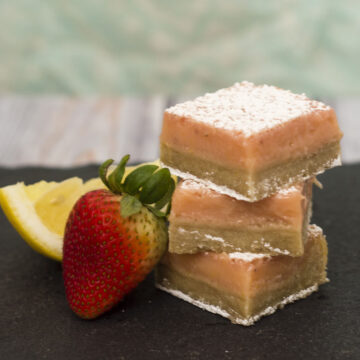 Strawberry lemon bars are a sweet twist on a tart classic bar cookie. These bars bring back memories of childhood summers drinking pink lemonade. #WhatsBaking TheRedheadBaker