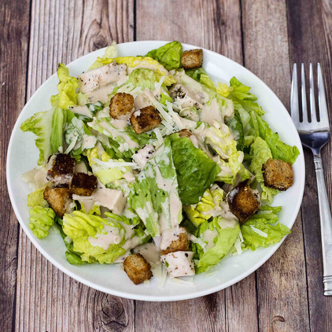 Lighter Caesar salad is delicious, and light on the calories. This version replaces most of the oil and the egg yolks in the dressing with fat-free Greek yogurt, making it creamy, but healthier.