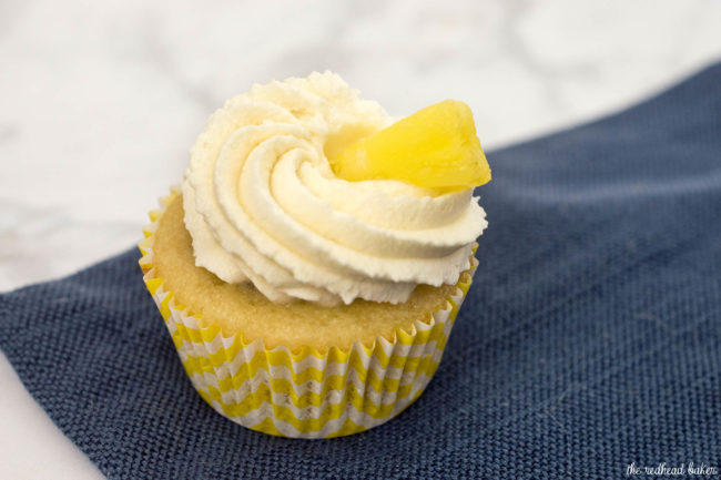 Pina colada cupcakes are soaked in rum syrup, filled with pineapple, and frosted with coconut whipped cream. A delicious summer treat! #SundaySupper