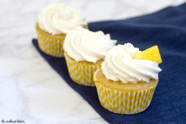 Pina colada cupcakes are soaked in rum syrup, filled with pineapple, and frosted with coconut whipped cream. A delicious summer treat! #SundaySupper