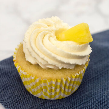 Pina colada cupcakes are soaked in rum syrup, filled with pineapple, and frosted with coconut whipped cream. A delicious summer treat! #SundaySupper