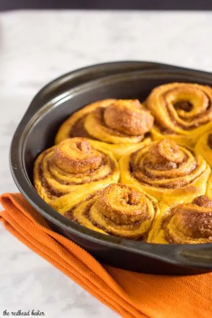 Pumpkin cinnamon rolls are a delicious way to start a fall morning! Sweet dough is flavored with pumpkin, rolled with a cinnamon filling, and topped with cream cheese drizzle. #PumpkinWeek