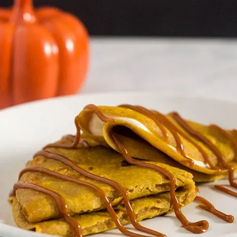 Pumpkin crepes are very thin dessert pancakes, folded over sweetened cream cheese filling and drizzled with dulce de leche. #PumpkinWeek