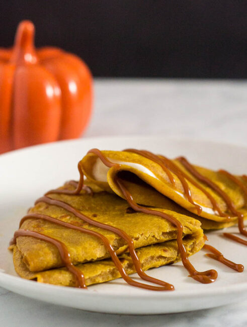 Pumpkin crepes are very thin dessert pancakes, folded over sweetened cream cheese filling and drizzled with dulce de leche. #PumpkinWeek