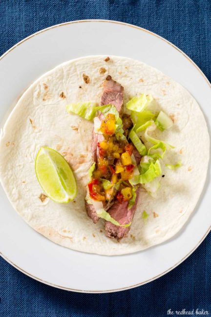 Flank steak tacos use a lean cut of beef, tenderized with a chile-lime marinade, as taco filling in soft tortillas, topped with shredded lettuce and pineapple salsa. #SundaySupper