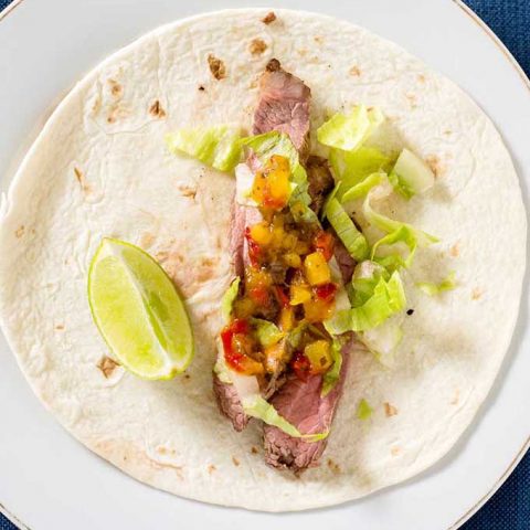 Flank steak tacos use a lean cut of beef, tenderized with a chile-lime marinade, as taco filling in soft tortillas, topped with shredded lettuce and pineapple salsa. #SundaySupper