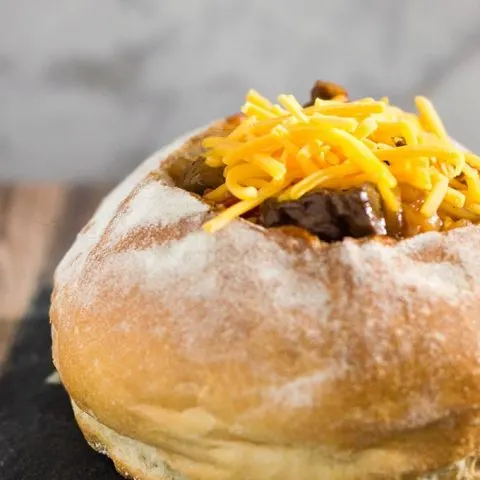 Philly cheesesteak chili has all the flavors of a traditional cheesesteak sandwich, topped with cheese and served in a hollowed-out bread bowl.