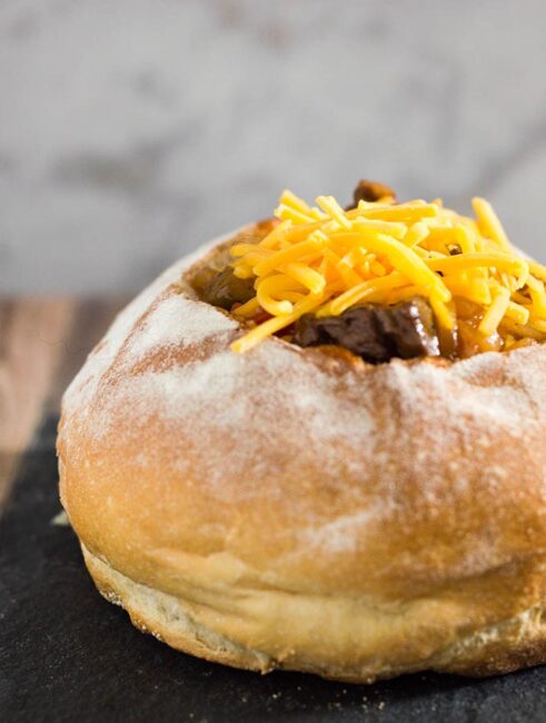 Philly cheesesteak chili has all the flavors of a traditional cheesesteak sandwich, topped with cheese and served in a hollowed-out bread bowl.