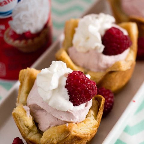 Mini raspberry mousse tartlets are full of spring flavor! Raspberry curd gives them a spring pink tint, and they are finished with a dollop of Reddi-wip®! #SpringReddi #ad