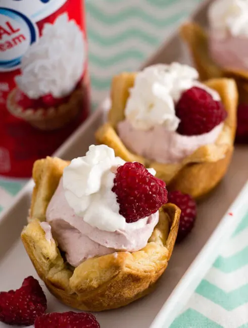 Mini raspberry mousse tartlets are full of spring flavor! Raspberry curd gives them a spring pink tint, and they are finished with a dollop of Reddi-wip&reg;! #SpringReddi #ad