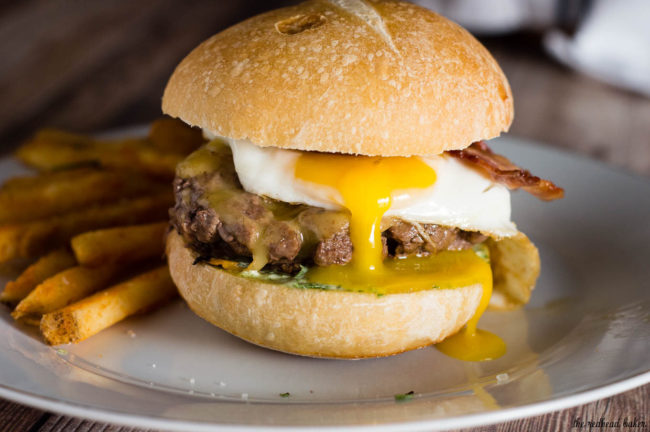 These French Bistro Burgers are full of over-the-top flavor: an herb aioli, smoked gouda cheese, bacon and a sunnyside up egg. Serve with rosemary fries or a frisee salad. #BurgerMonth #GirlCarnivore