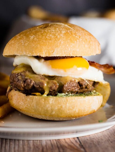 These French Bistro Burgers are full of over-the-top flavor: an herb aioli, smoked gouda cheese, bacon and a sunnyside up egg. Serve with rosemary fries or a frisee salad. #BurgerMonth #GirlCarnivore