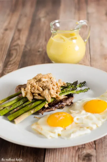The classic brunch staple of steak and eggs gets fancy! The steak is served Oscar-style with asparagus, crab meat and Hollandaise sauce, with two sunny side-up eggs. #BrunchWeek
