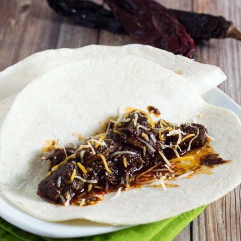 Authentic barbacoa beef tacos are piled with shredded beef cooked low and slow in chili-pepper spiced sauce, and topped with cilantro, salsa and lime wedges.