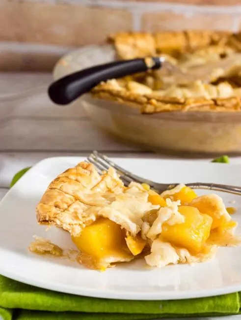 One slice of this mango peach pie is a tropical treat! Chunks of fresh fruit are lightly spiced with cinnamon, ginger and nutmeg.  #OXOGoodCookies #BakeADifference