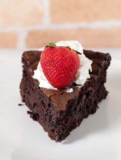 Naturally gluten-free flourless chocolate cake is rich, dense, and has intense chocolate flavor. Top with whipped cream, ice cream or fruit sauce. #Choctoberfest