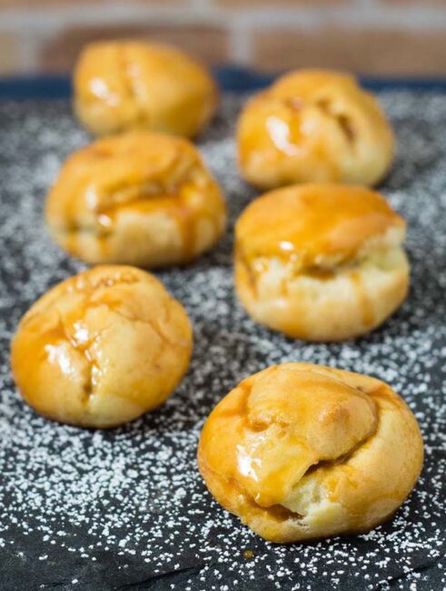 Pumpkin cream puffs are filled with creamy pumpkin custard and dunked in caramel glaze. You've never had a pumpkin dessert like this before! #PumpkinWeek