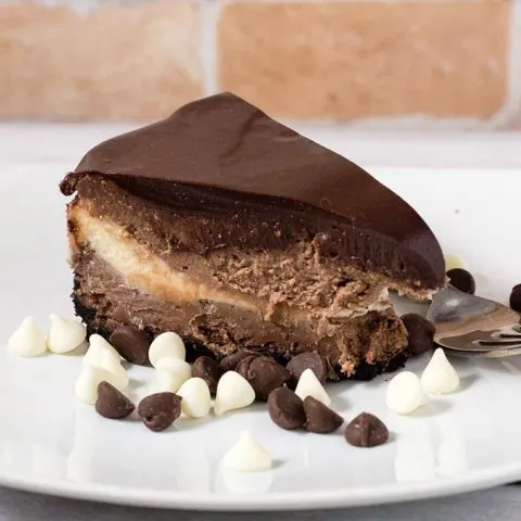 If chocolate cheesecake is good, triple chocolate cheesecake must be better! Layers of semisweet, white and milk chocolate cheesecake on a chocolate cookie crust are topped with a rich chocolate glaze. #Choctoberfest