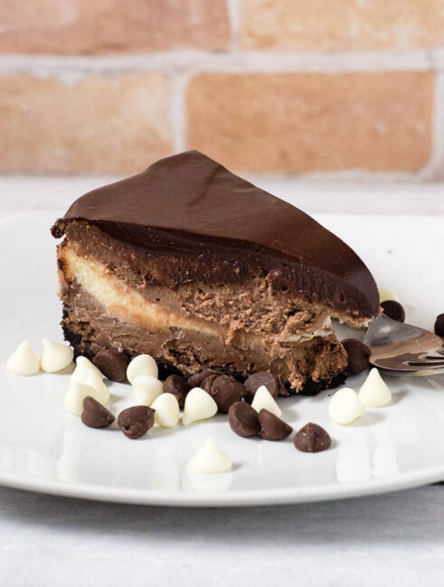 If chocolate cheesecake is good, triple chocolate cheesecake must be better! Layers of semisweet, white and milk chocolate cheesecake on a chocolate cookie crust are topped with a rich chocolate glaze. #Choctoberfest