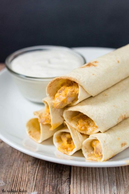 A plate of baked buffalo chicken taquitos and ranch dipping sauce.